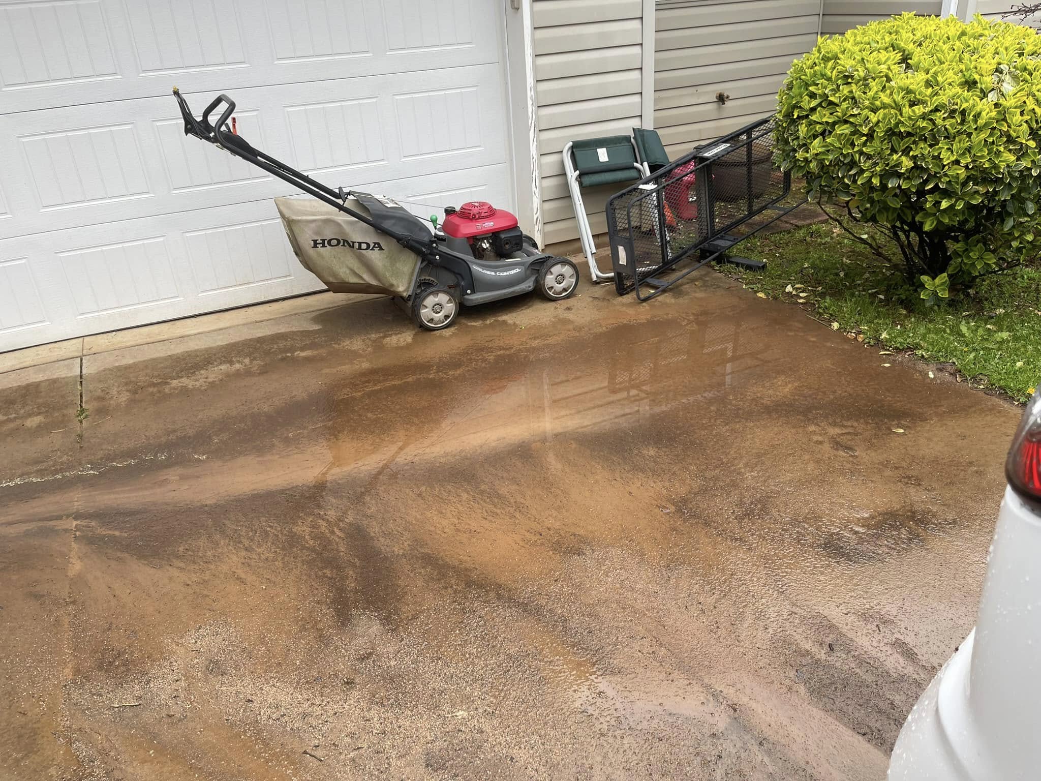 Homeowner inspecting driveway grade and checking for water pooling issues in Sudbury Ontario