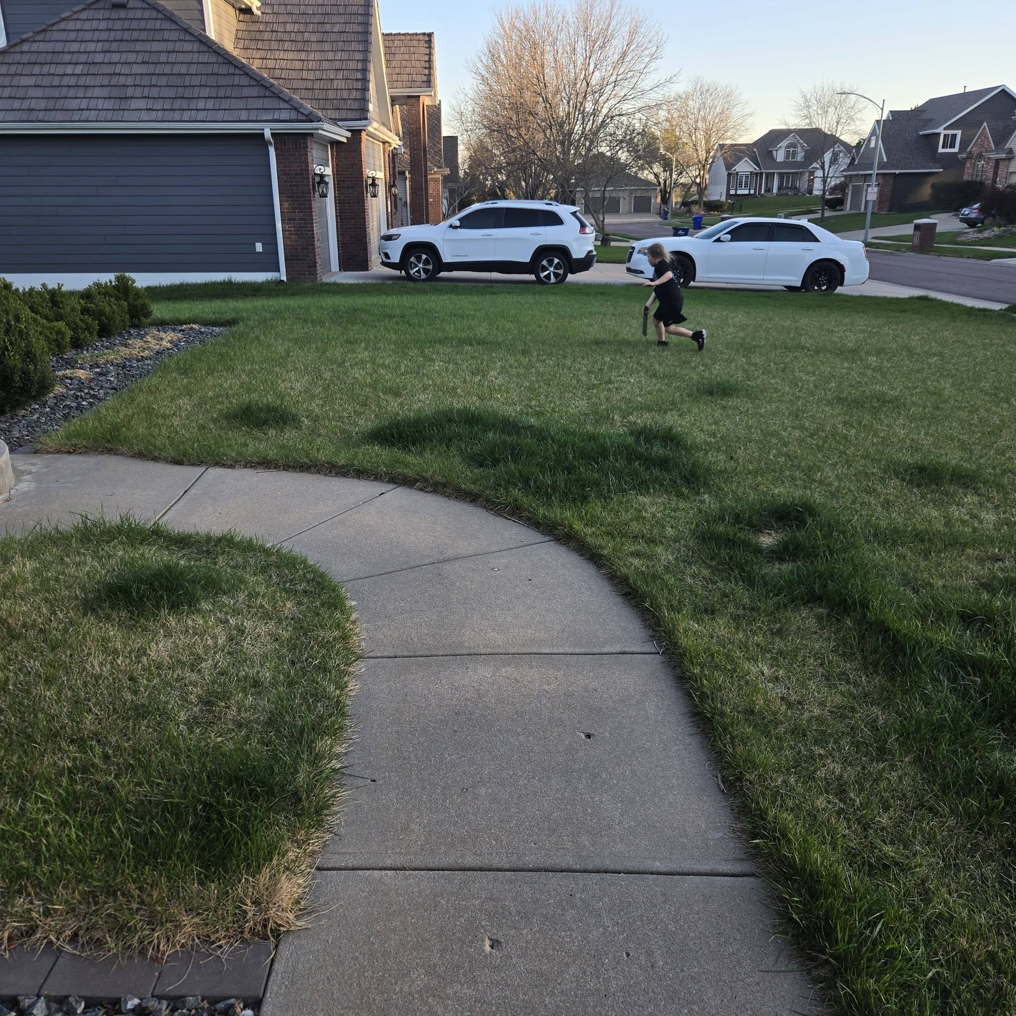 Teenage lawn care worker observing soil and grass conditions carefully on a Sudbury Ontario property