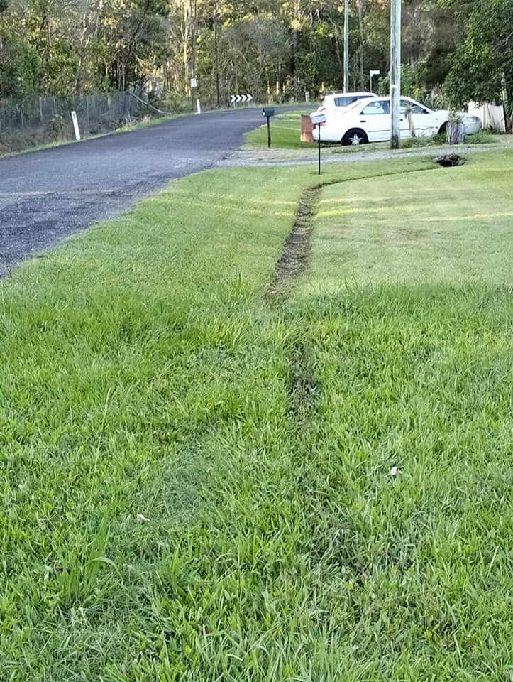Neighbour downspout directing water runoff toward Sudbury property lawn edge